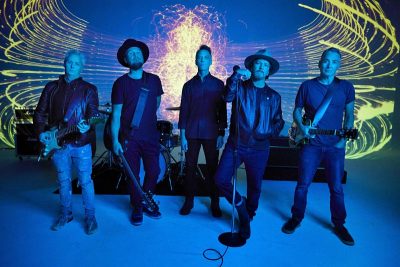 Die Mitglieder von Pearl Jam stehen in einer blauen Stdioumgebung.